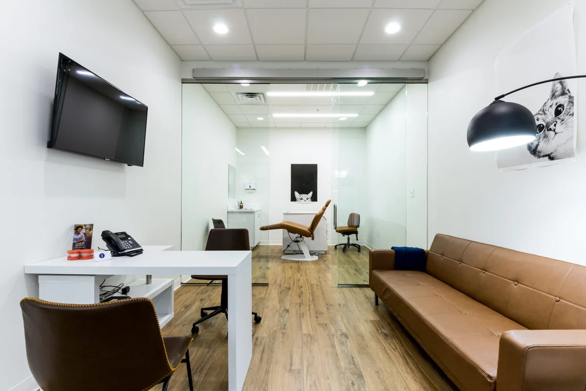 Sala de espera clínica luminosa con sofá y sillón al fondo