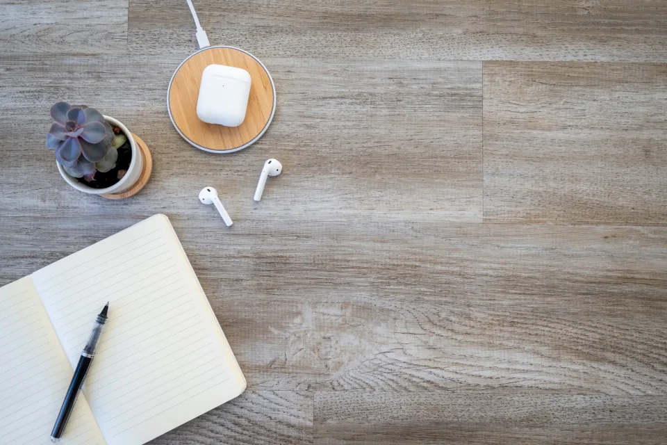 Auriculares junto a un cuaderno abierto sobre una mesa de madera