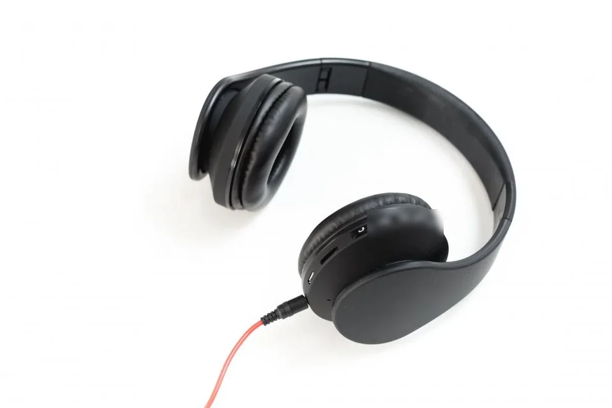 Auriculares negros de diadema con cable rojo sobre un fondo blanco