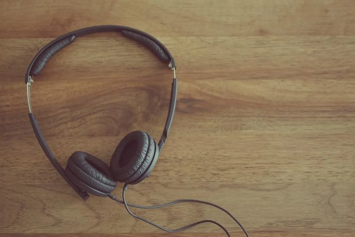 Unos auriculares de diadema con cable apoyados sobre una mesa de madera clara