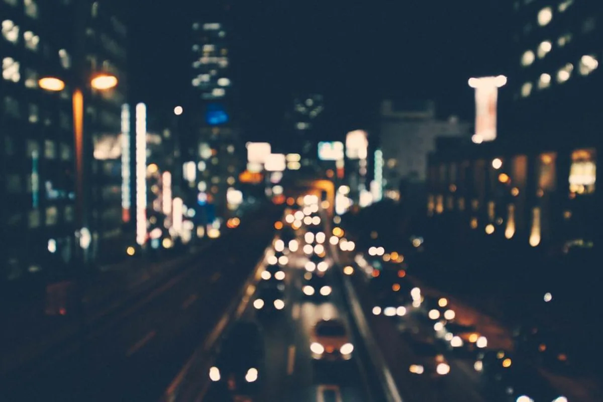 Avenida de ciudad de noche con edificios iluminados y las luces de los coches desenfocadas