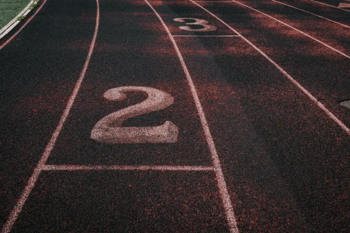 Calles de una pista de atletismo de color rojo oscuro con los números dos y tres pintados en blanco