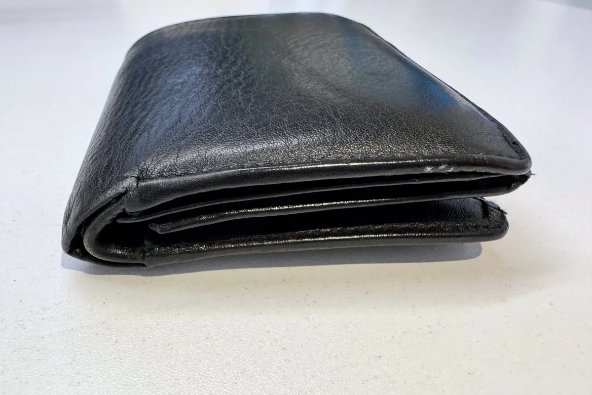 Cartera de piel negra cerrada sobre una superficie blanca