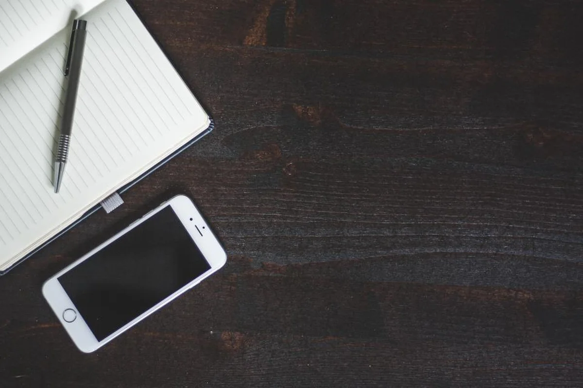 Libreta y teléfono móvil apagado sobre una mesa de madera