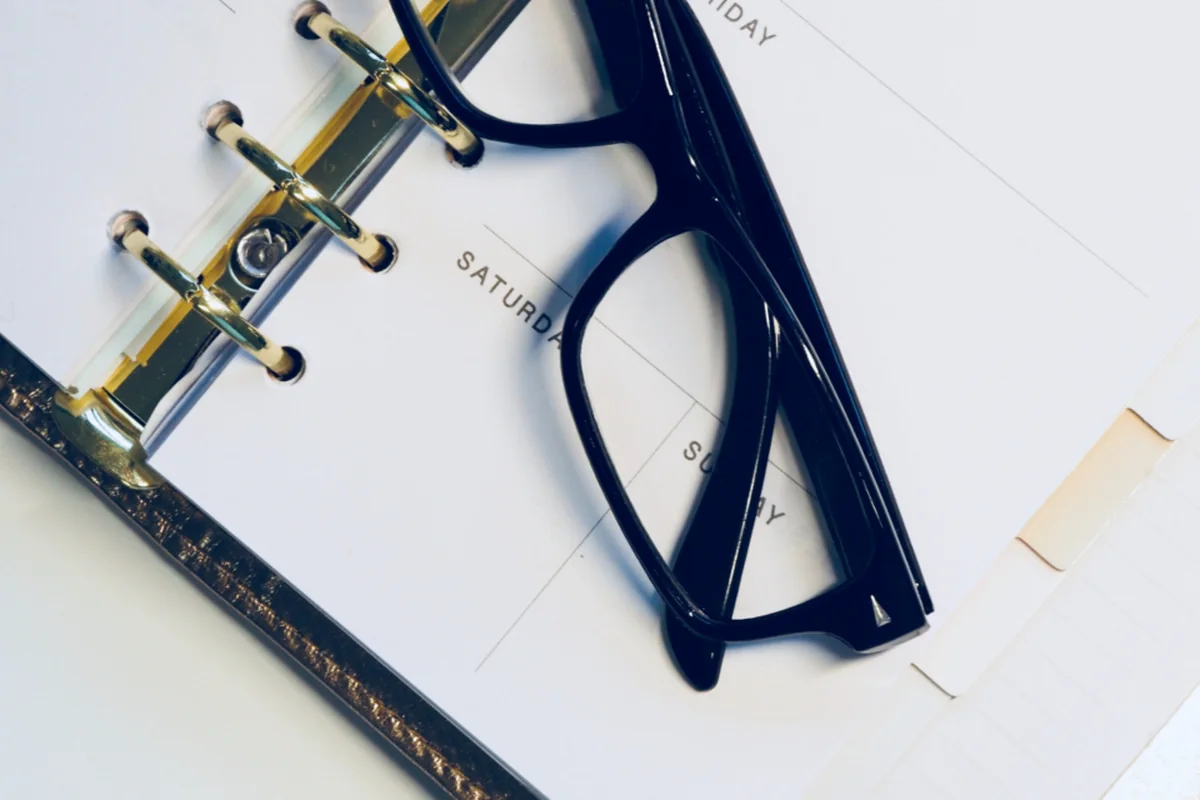 Unas gafas sobre una agenda de papel abierta por los días de la semana