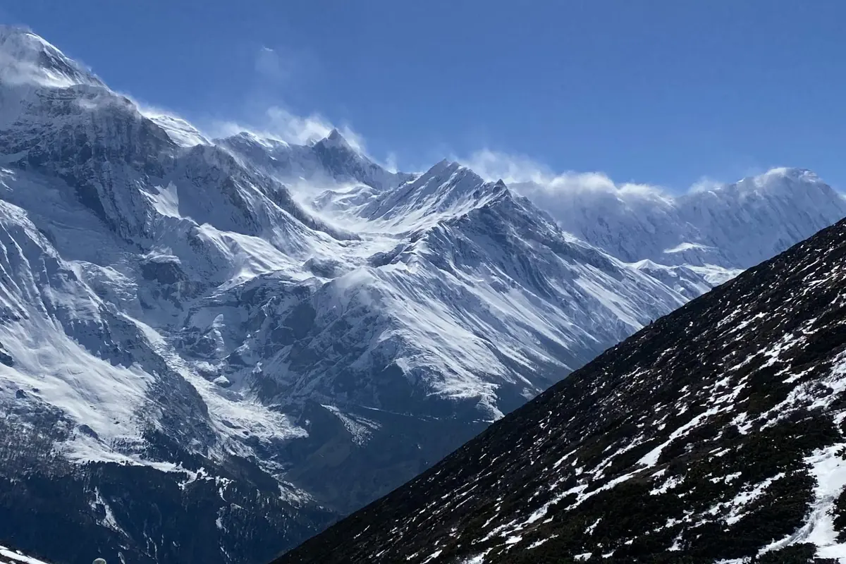 Sendero de montaña nevado con picos al fondo