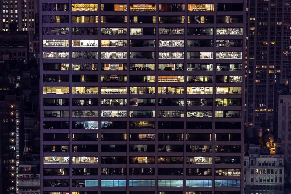 Fachada de un edificio alto de noche con decenas de ventanas iluminadas