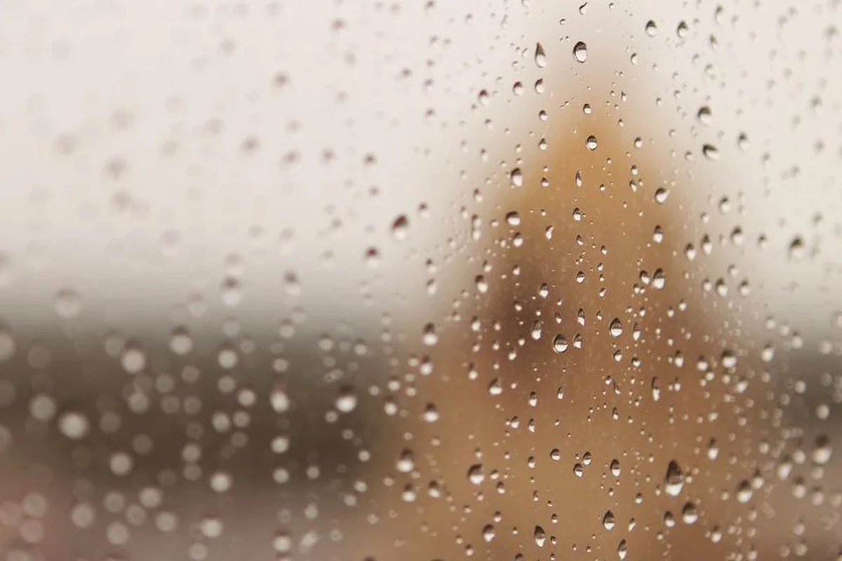 Gotas de lluvia sobre un cristal con el fondo desenfocado en tonos beis y marrones