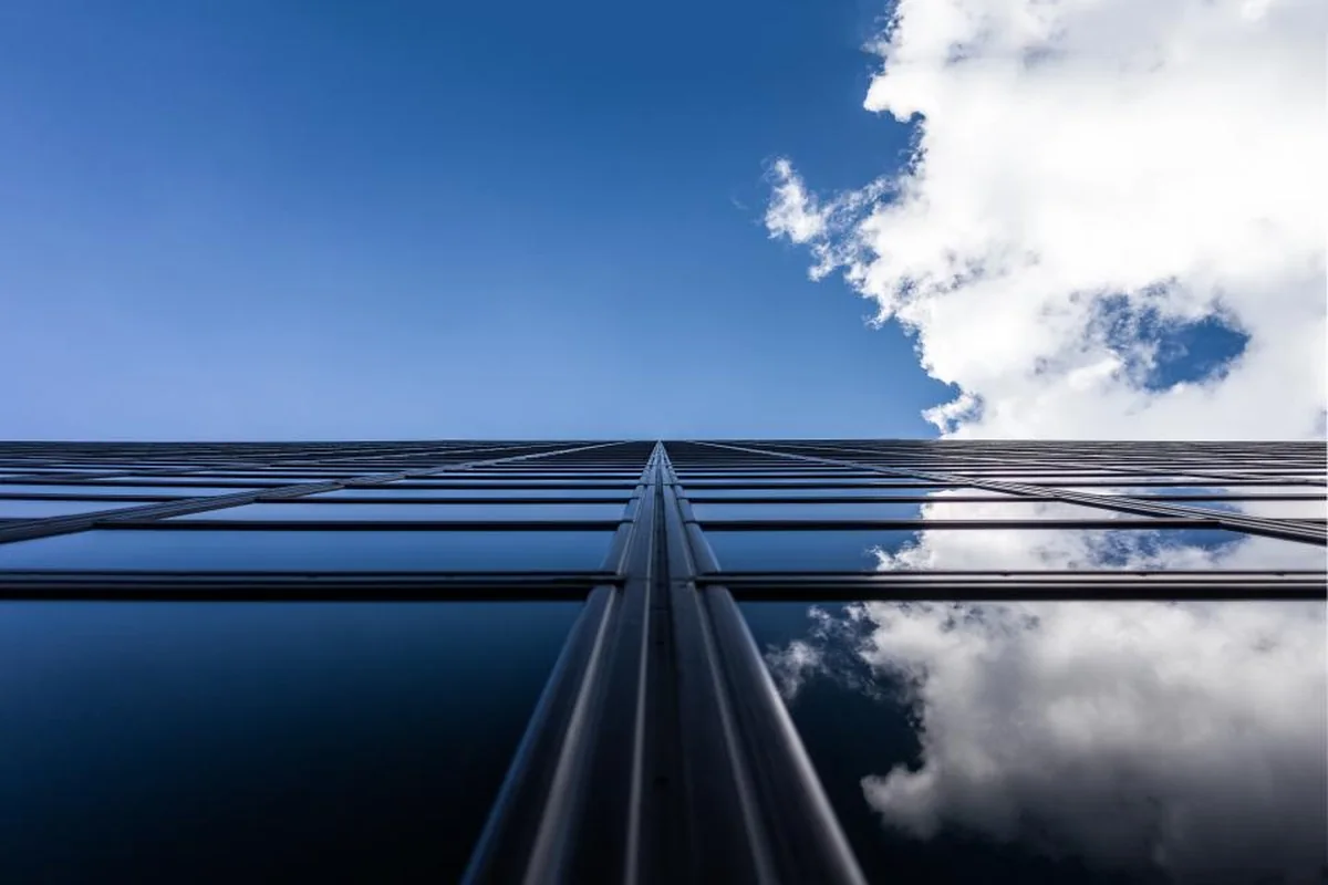Cielo azul con nubes junto al borde de un edificio de cristal