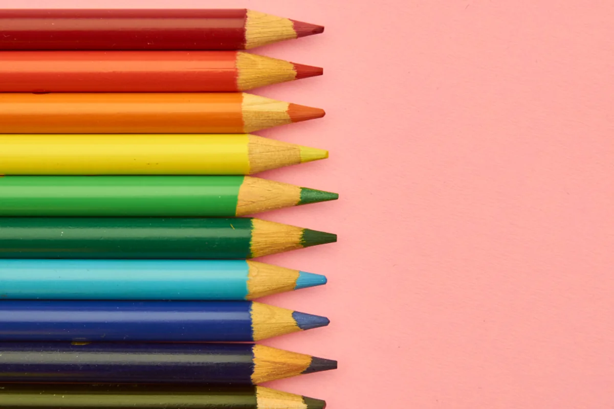 Lápices de colores alineados uno debajo de otro sobre un fondo rosa