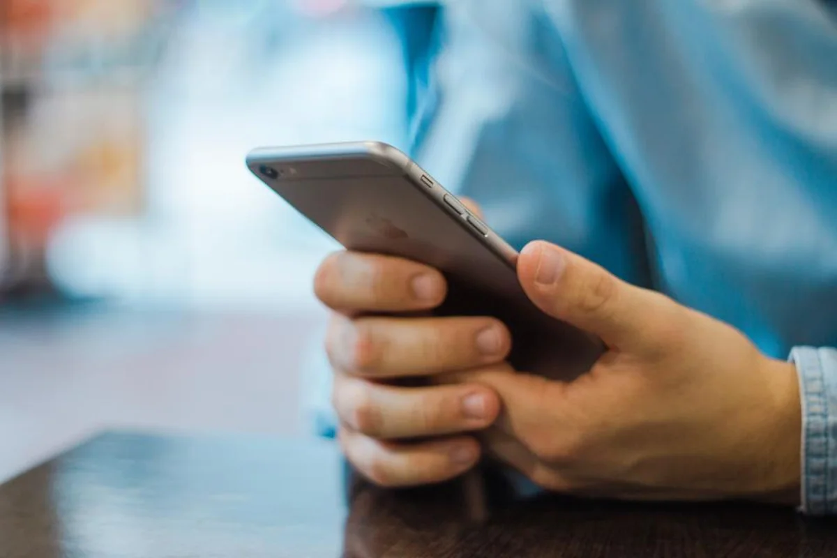 Primer plano de unas manos sujetando un smartphone sobre una mesa