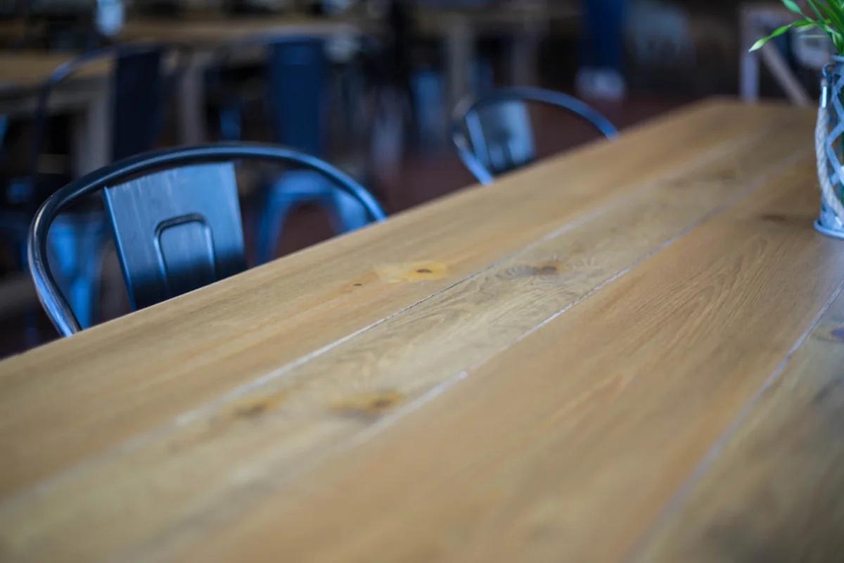 Primer plano de una mesa larga de madera con sillas metálicas vacías alrededor en una oficina desenfocada