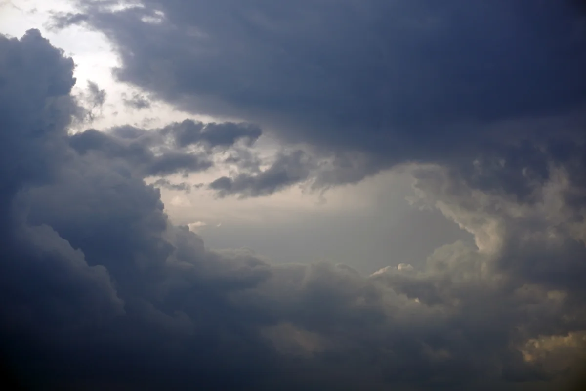 Cielo cubierto de nubes oscuras con un claro de luz que se abre entre ellas