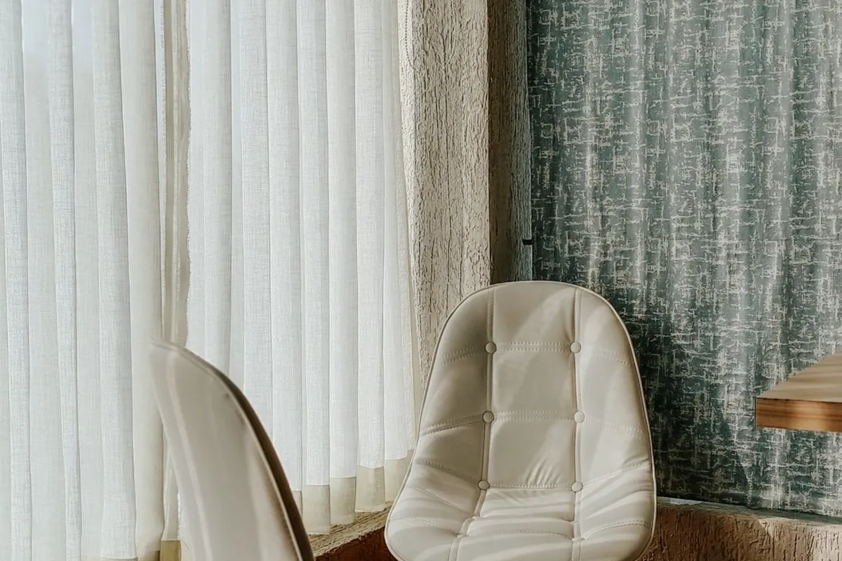Una silla individual junto a una ventana con cortinas
