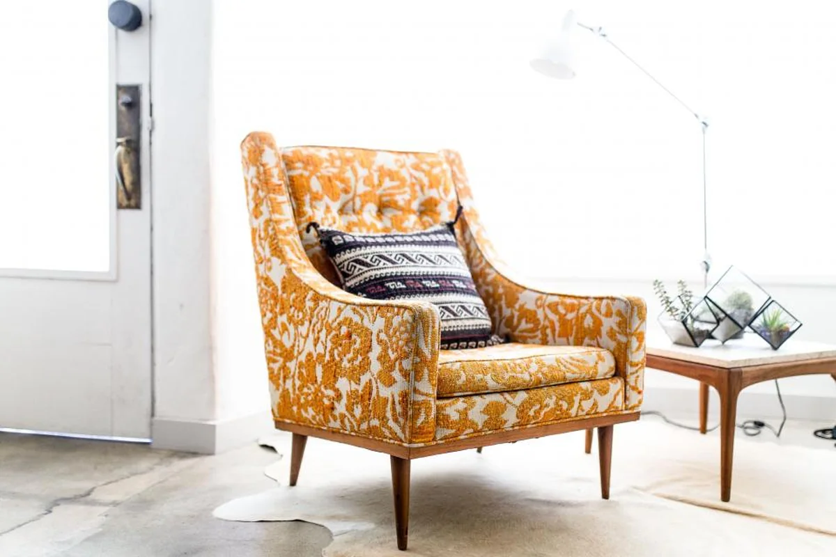Sillón individual de color naranja vacío junto a una lámpara de pie