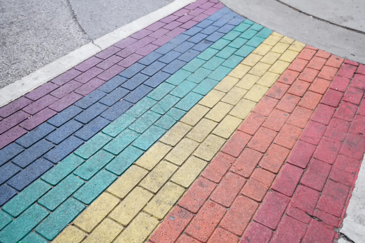 Paso de peatones de ladrillo pintado con los colores del arcoíris en una calle
