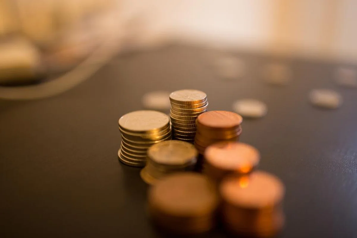 Pequeñas pilas de monedas sobre una mesa oscura con fondo desenfocado