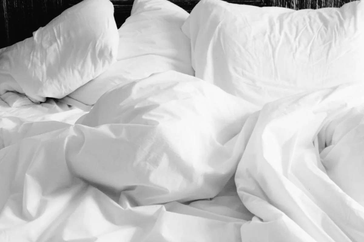 Sábanas blancas y almohadas revueltas sobre una cama deshecha