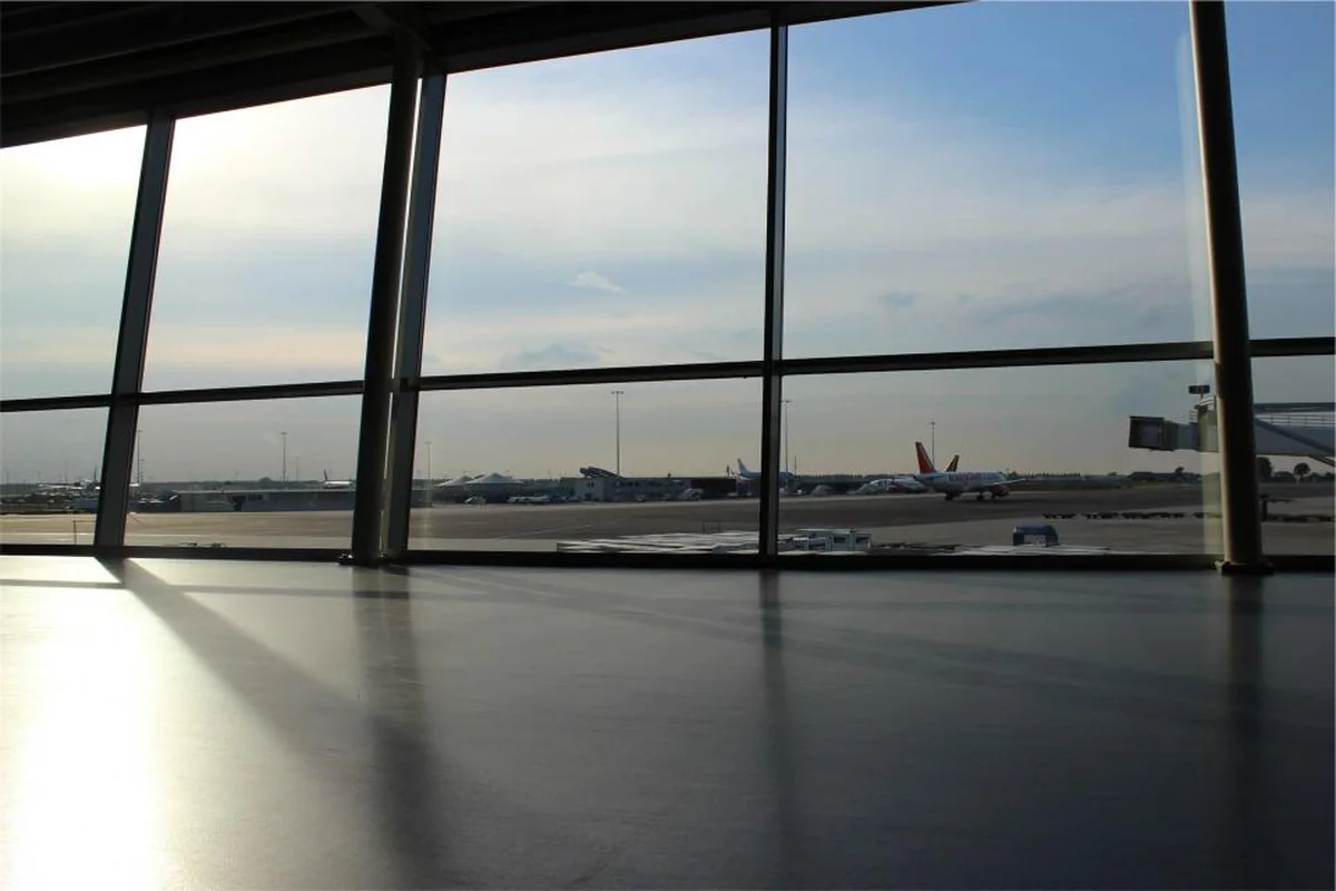 Terminal de aeropuerto vacía con grandes ventanales por los que se ven aviones en la pista