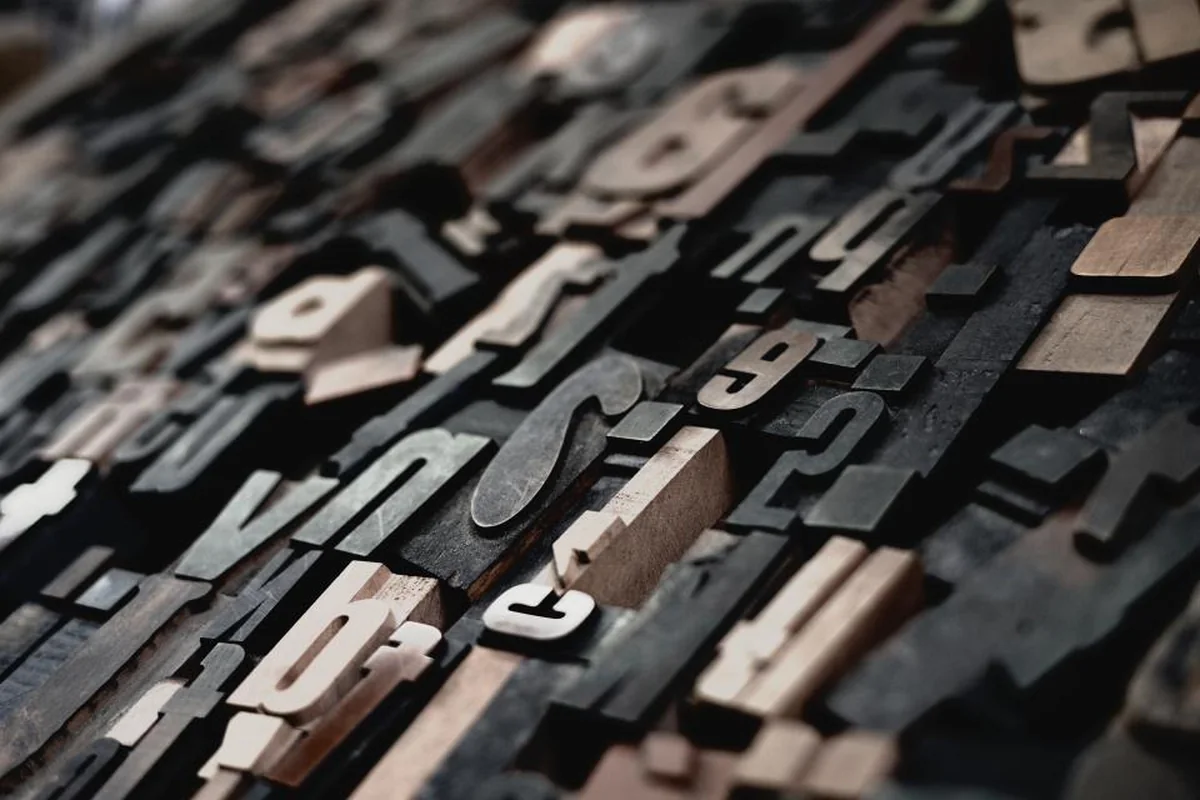 Montón de tipos de imprenta de madera y metal con letras sueltas, vistos de cerca y en diagonal