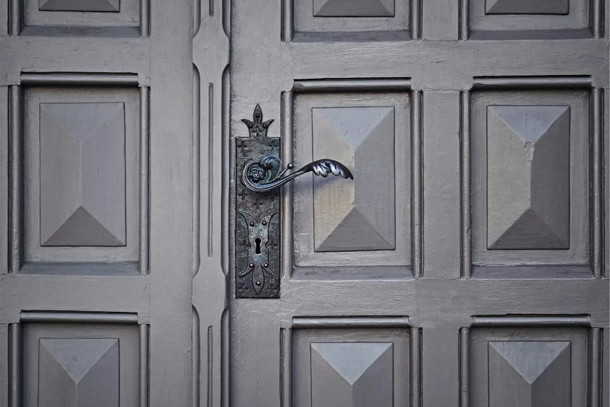 Puerta de madera antigua con picaporte metálico ornamentado
