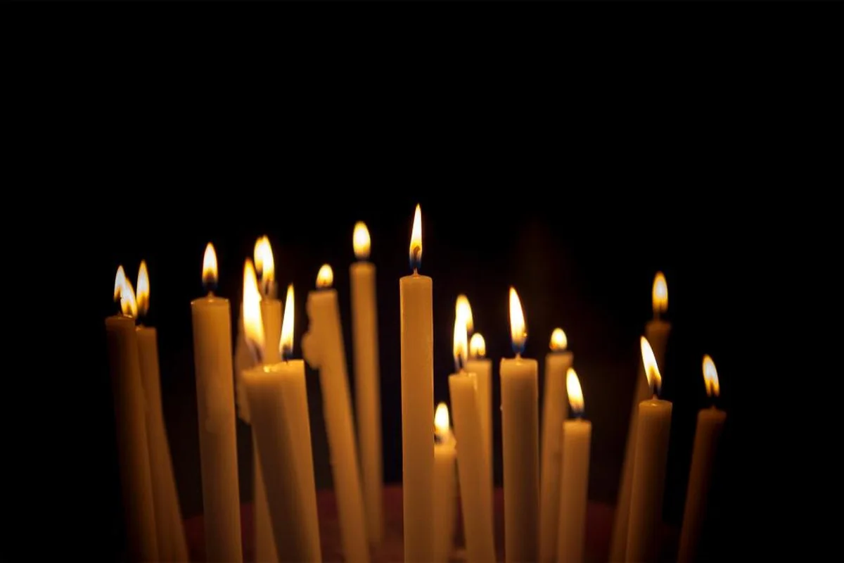 Grupo de velas largas encendidas sobre un fondo completamente oscuro